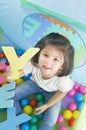 Little smiling girl playing lying in ball park. Girl learning the letters