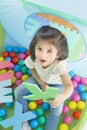 Little smiling girl playing lying in ball park. Girl learning the letters Royalty Free Stock Photo