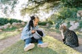 Little smiling girl sits with a hat with kittens on the green grass near the cat Royalty Free Stock Photo