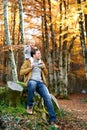 Little smiling girl sits on the shoulders of her dad sitting on a stump in an autumn park Royalty Free Stock Photo