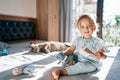 Little smiling girl sitting on the bed with a toy cat and a comb in her hands Royalty Free Stock Photo