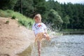 Happy child playing in the lake. Kid having fun outdoors Royalty Free Stock Photo