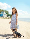 Little smiling girl walking with dog on the beach Royalty Free Stock Photo