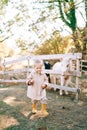 Little smiling girl walks along the path from the pony in the paddock Royalty Free Stock Photo