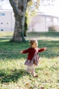 Little smiling girl walks on a green lawn waving her hands Royalty Free Stock Photo