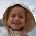 A little smiling girl is wearing a raincoat jacket with hood against the stormy sky. Childhood concepts. Environmental concepts. Royalty Free Stock Photo