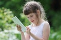 Little smiling girl in white dress plays with tablet pc Royalty Free Stock Photo