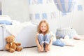 Little smiling girl in a white T-shirt and jeans sits on the background of a decorative balloon. The child plays in the children`s