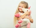 Little smiling girl with white unicorn toy.
