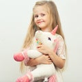 Little smiling girl with white unicorn toy.