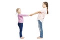 Little smiling girls with pigtails in jeans and pink sweaters hold hands. Full height. Isolated over white background