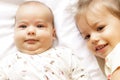 Little smiling kids playing together sitting on bed. Brother and sister kiss a newborn.Toddler kid meeting new born Royalty Free Stock Photo