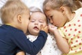 Little smiling kids playing together sitting on bed. Brother and sister kiss a newborn.Toddler kid meeting new born Royalty Free Stock Photo