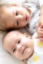 Little smiling kids playing together sitting on bed. Brother and sister show a newborn a toy. kids meeting new born Royalty Free Stock Photo