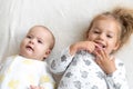 Little smiling kids playing together sitting on bed. Brother and sister show a newborn a toy. kids meeting new born Royalty Free Stock Photo