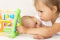 Little smiling kids playing together sitting on the bed. Brother and sister show a newborn a toy. Toddler kids meeting Royalty Free Stock Photo