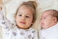 Little smiling kids playing together sitting on the bed. Brother and sister show a newborn a toy. Toddler kids meeting Royalty Free Stock Photo