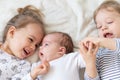 Little smiling kids playing together sitting on the bed. Brother and sister show a newborn a toy. Toddler kids meeting Royalty Free Stock Photo