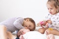 Little smiling kids playing together sitting on the bed. Brother and sister show a newborn a toy. Toddler kids meeting Royalty Free Stock Photo