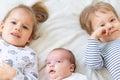 Little smiling kids playing together sitting on the bed. Brother and sister show a newborn a toy. Toddler kids meeting Royalty Free Stock Photo