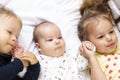 Little smiling kids playing together sitting on the bed. Brother and sister show a newborn a toy. Toddler kids meeting Royalty Free Stock Photo