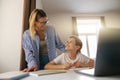 Little smiling schoolboy using laptop to do school homework with help of his mom Royalty Free Stock Photo