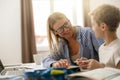 Smiling mom helping her son doing homework studying online using laptop in home Royalty Free Stock Photo