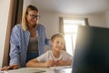 Smiling mom helping her son doing homework studying online using laptop in home Royalty Free Stock Photo