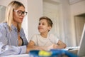 Smiling mom helping her son doing homework studying online using laptop in home Royalty Free Stock Photo