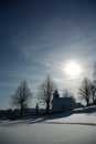 Kaplnka zaviatá snehom pred západom slnka