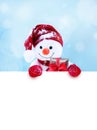 Little snowman in cap and scarf on snow in the winter. Background with a funny snowman. Christmas card.