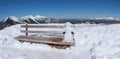 Little snowman sitting at a wooden bench in the bavarian alps