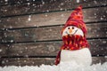 Little snowmans on soft snow on wooden background