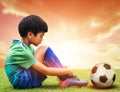 Little soccer football playing sitting sadly with football on his side after losing a sport game