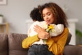 Young mixed race woman mother with flower bouquet embracing son while getting congratulations on Mother`s day Royalty Free Stock Photo