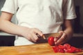 Little son learning to cut tomatoes. Chef is cutting vegetables for salad on a chopping board, close up Royalty Free Stock Photo