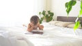 Little son lies on the bed in the bedroom and looks at Internet Tablet