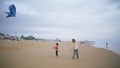 Little son playing kite with parent on beach. Joyful mother helping teach child Royalty Free Stock Photo