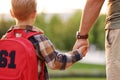 Little son schoolboy with backpack holding hand of father dad while going to first grade in school Royalty Free Stock Photo