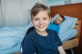 Little son sitting on chair near his sick father sleeping on hospital bed at ward Royalty Free Stock Photo