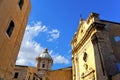 Little square with old classical colorful buildings, church dome and cloudy blue sky in coastal town Licata in Sicily, Italy