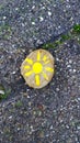 Little stone painted with the sun on the asphalt