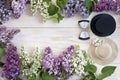 Little straw hat and cylinder with lilac branches on a white wooden background.