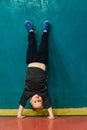 Little boy in sportswear stands on his hands near the wall in th Royalty Free Stock Photo