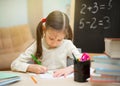 Little student. Beautiful young girl is teaching at home on blac Royalty Free Stock Photo