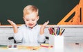 Little student boy happy with an excellent mark. Kid is learning in class on background of blackboard. Little children Royalty Free Stock Photo