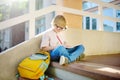 Little student doing homework on break on stair of elementary school building. Portrait of funny nerd schoolboy with big glasses. Royalty Free Stock Photo