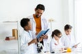 A little student group with male teacher in white lab coat do experiment in classroom together. A boy presentation recorded Royalty Free Stock Photo