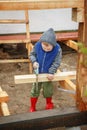 Little studious boy sawing a wooden board. Home construction. Li