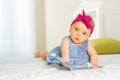 Little stylish baby girl leaf through book in bed Royalty Free Stock Photo